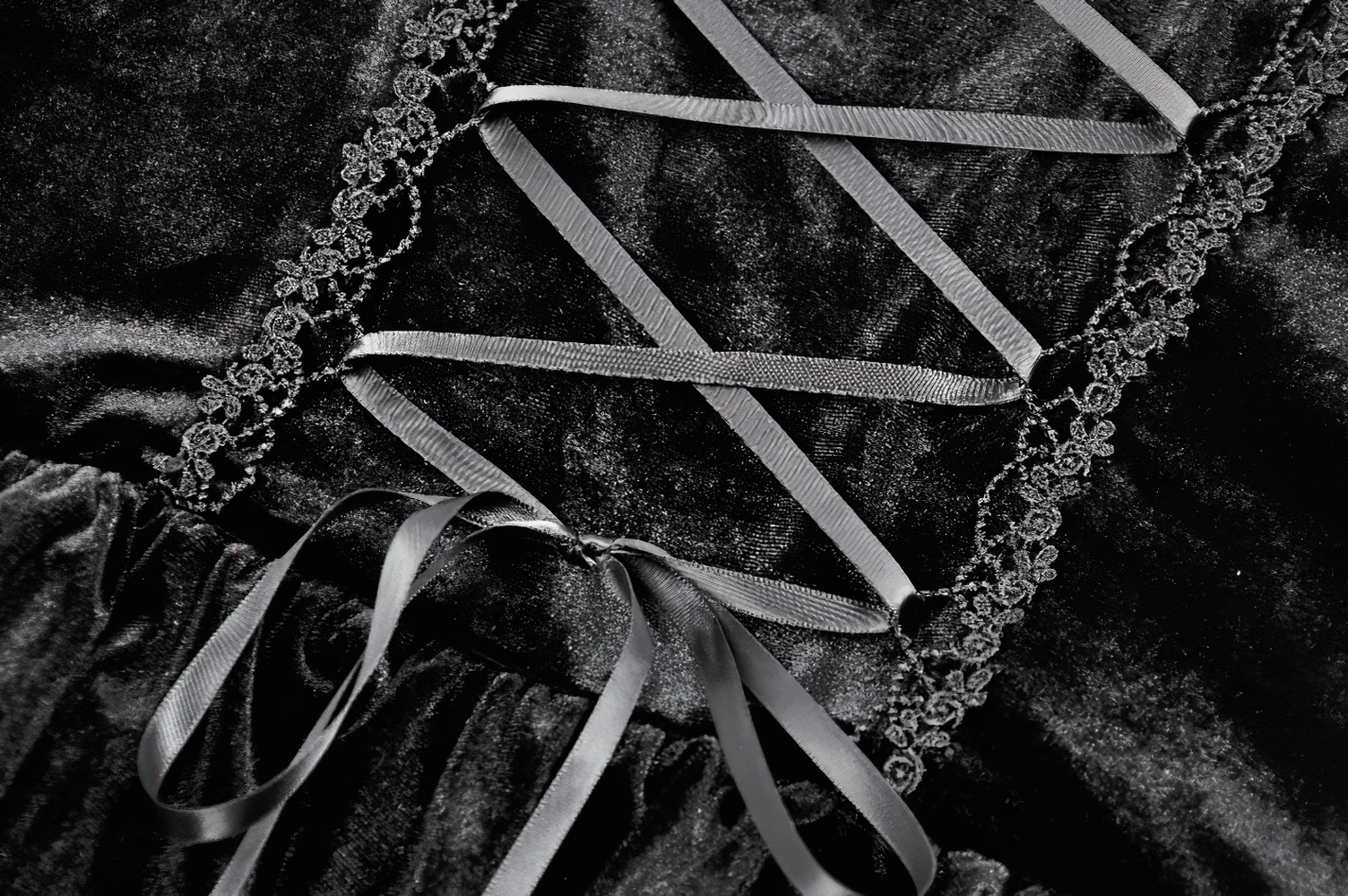 Close-up of black velvet lace-up bodice with ruffles and intricate lace trim for a Gothic mini dress.