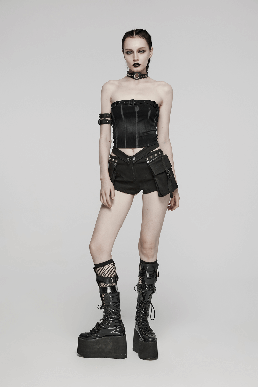 Edgy women's strapless tube top with buckle detail, paired with stylish black shorts and bold platform boots.