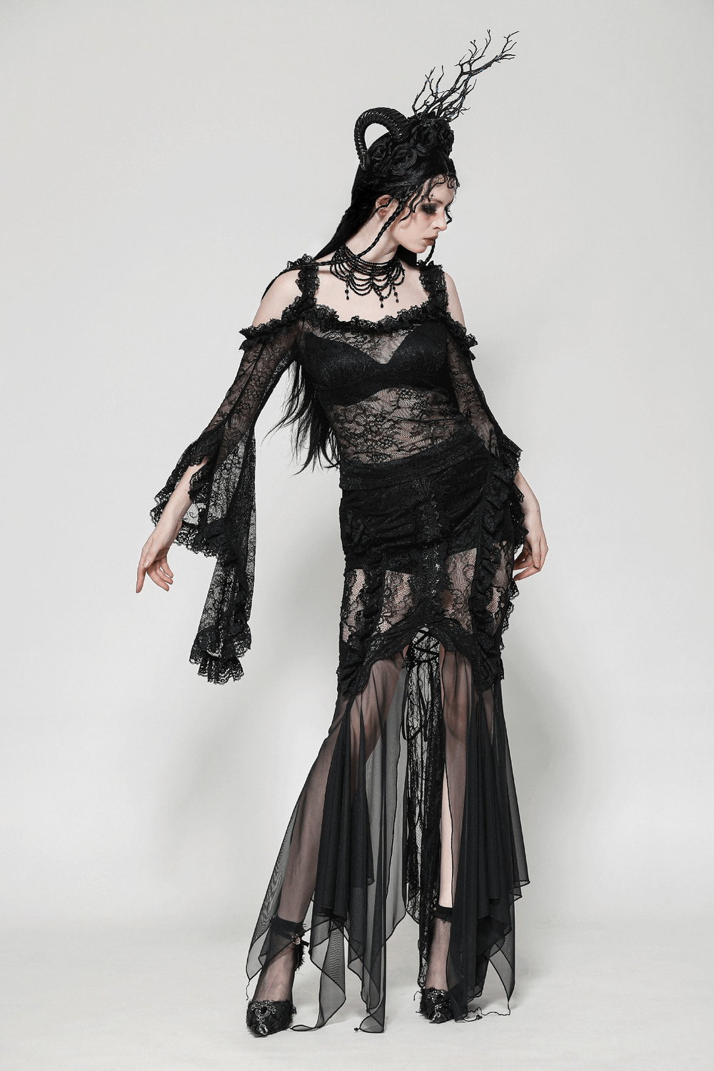 Model showcasing a sheer black lace top with dramatic draped bell sleeves, embodying gothic elegance and dark romance.