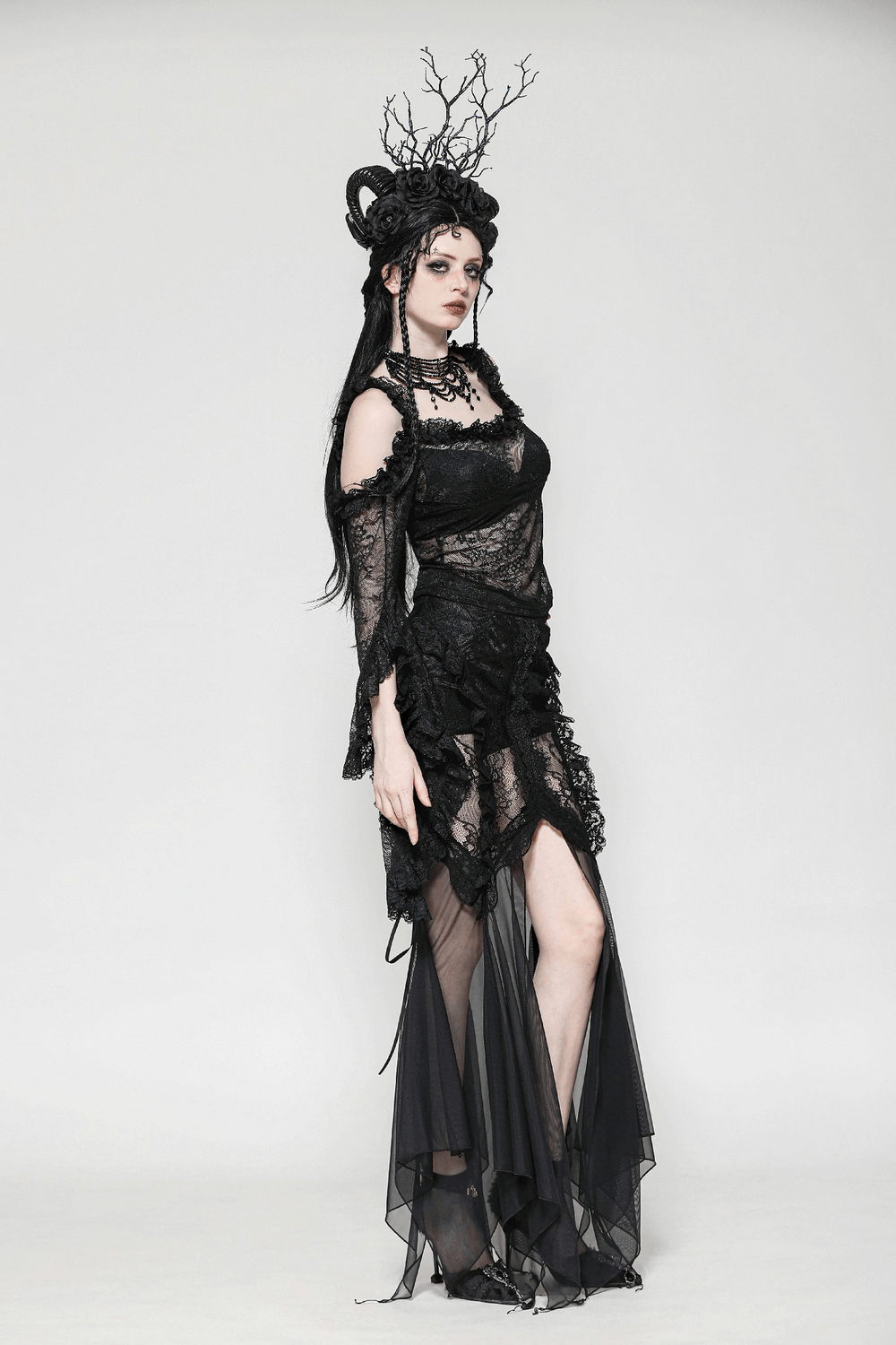 Gothic model in sheer black lace top and flowing skirt, showcasing dramatic bell sleeves and dark romantic elegance.