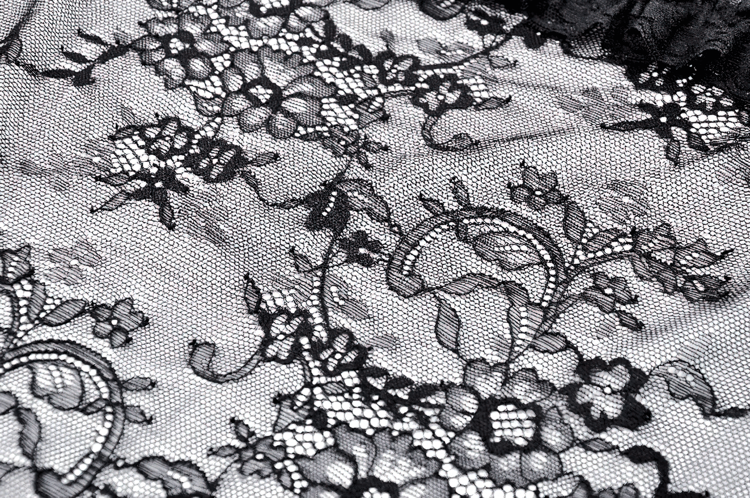 Sheer black lace fabric with intricate floral patterns for gothic and romantic styles.