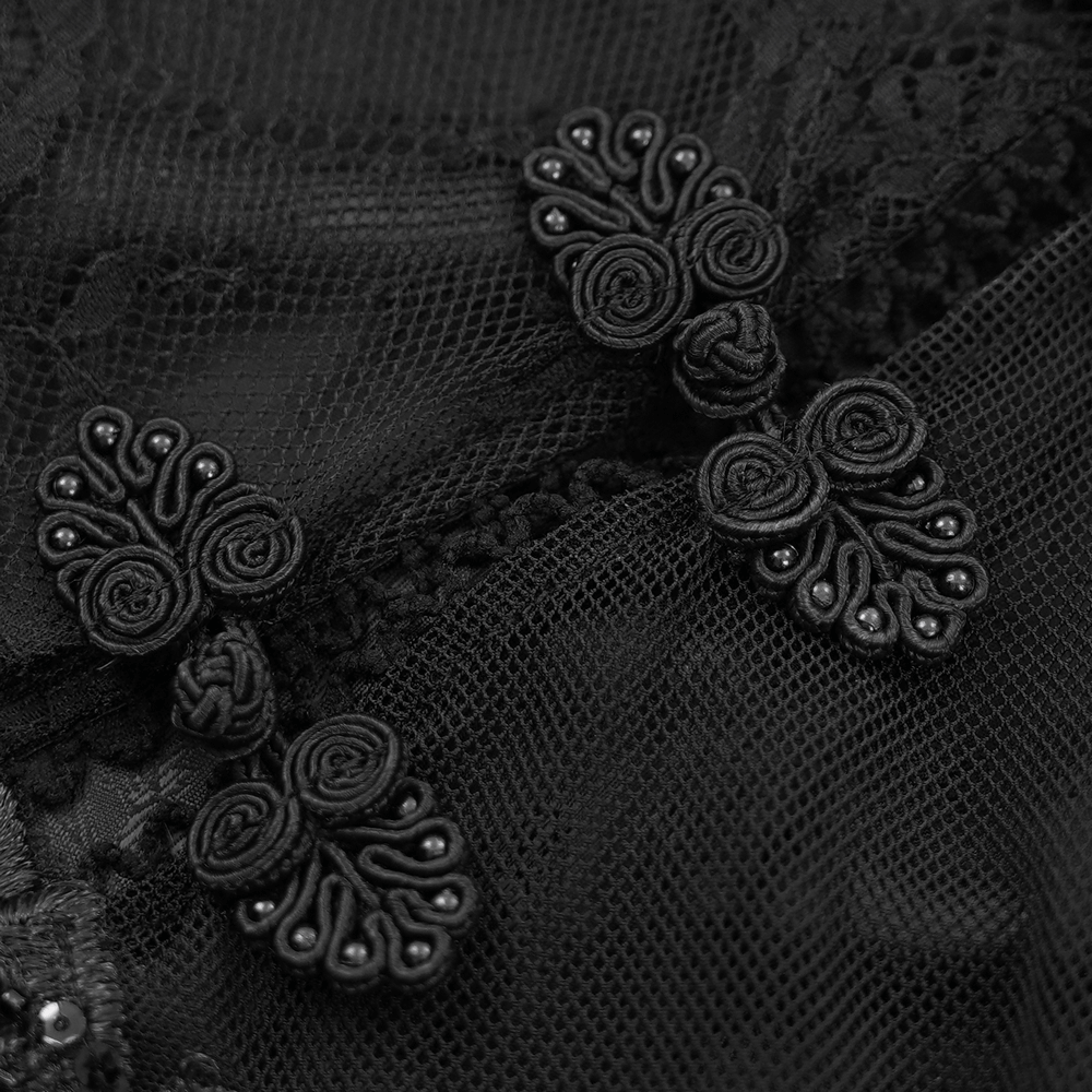 Close-up of intricate black appliques on sheer lace, adding elegance and gothic flair to a stunning dress.