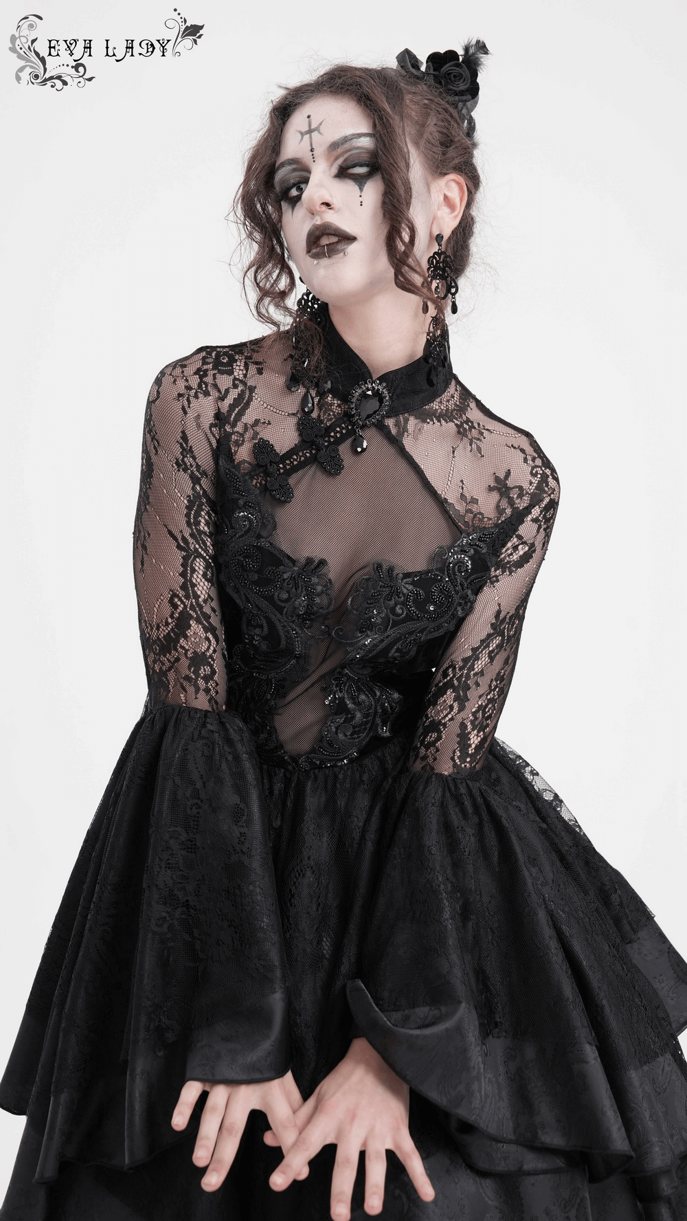 Elegant model in a sheer lace dress with flared sleeves and intricate appliques, showcasing gothic fashion style.