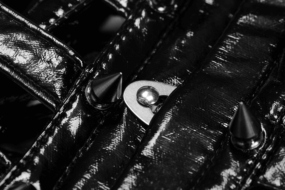 Close-up of shiny black patent PU corset belt featuring metal spikes and buckles for a punk style.