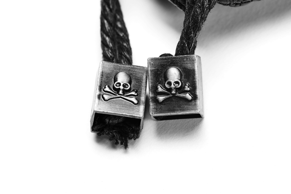 Close-up of silver skull and crossbones metal tips on black cord, adding edgy detail to punk accessories.