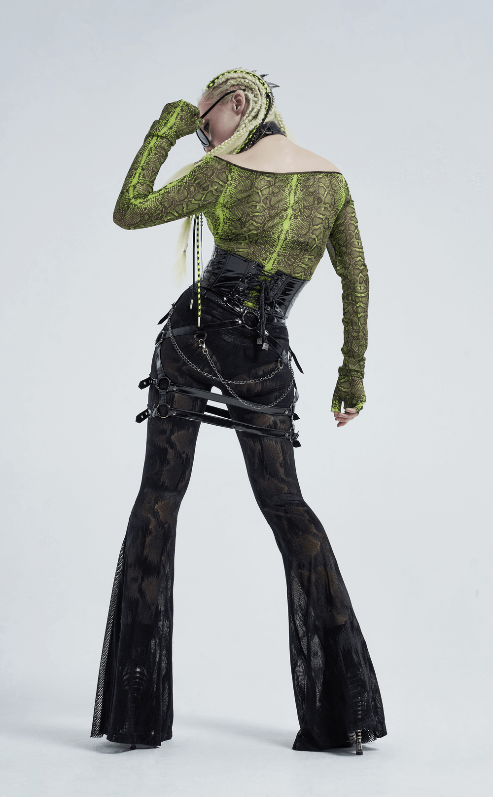 Model showcasing a stylish punk outfit with a green lace top and black corset-style pants, highlighting edgy fashion.