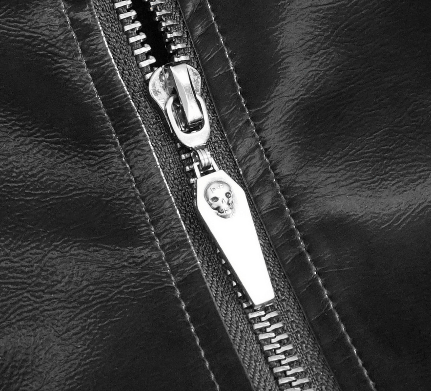 Close-up of a stylish black jacket zipper featuring a skull pull tab, perfect for gothic fashion enthusiasts.