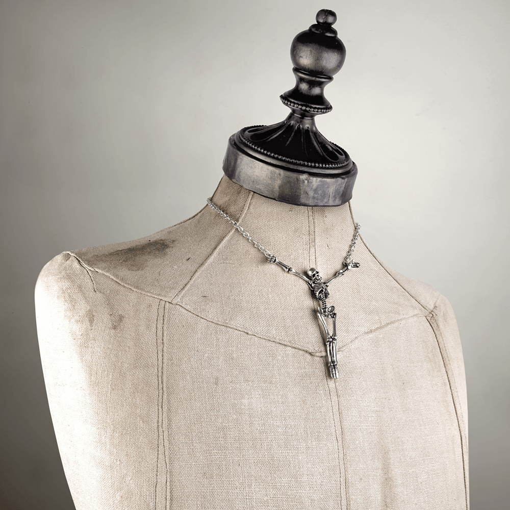Skeleton cross pendant necklace on a vintage mannequin, showcasing detailed pewter design and gothic charm.