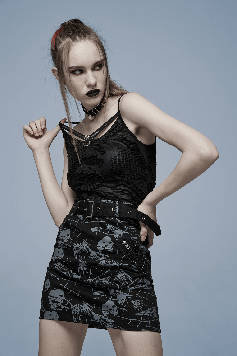 Model showcasing a gothic lace camisole with skull trim, paired with a skull print mini skirt, exuding edgy style.