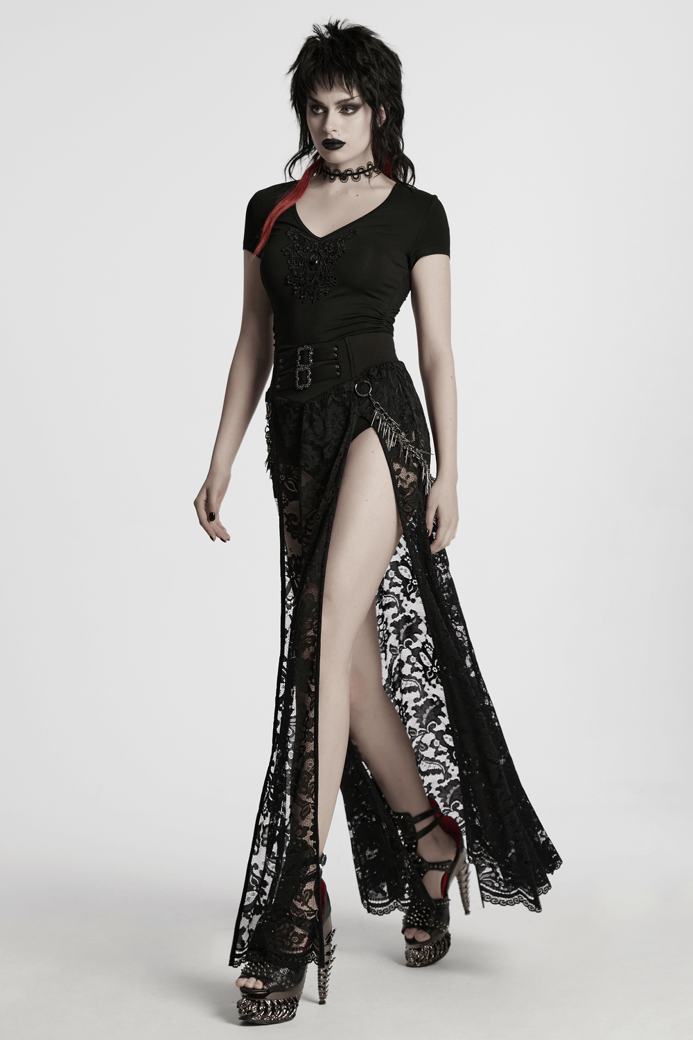 Stylish woman in black lace skirt and V-neck top, showcasing gothic fashion with bold accessories.