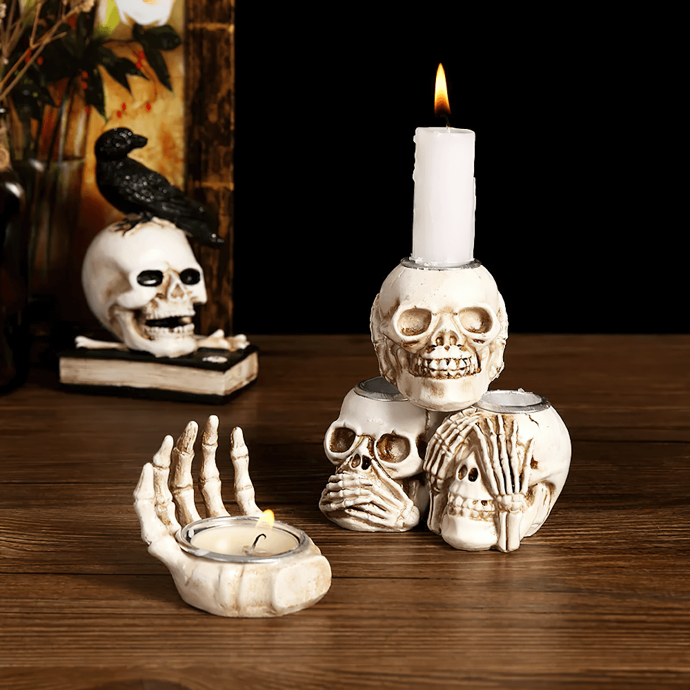 Set of spooky skull candle holders with skeleton hand design for Halloween decor.