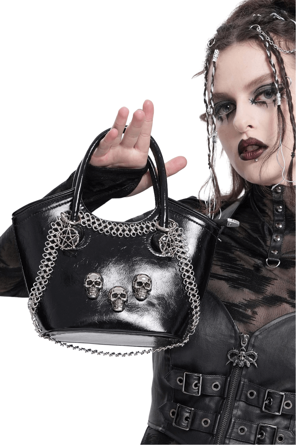 Gothic tote bag with skull accents and chain detailing held by model in edgy outfit.