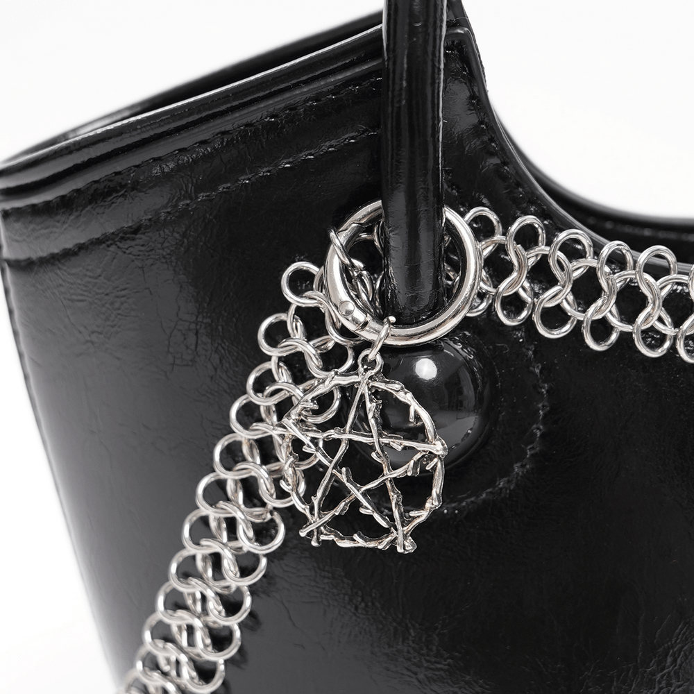 Close-up of a gothic tote bag featuring a silver pentagram charm and chain-link detailing.