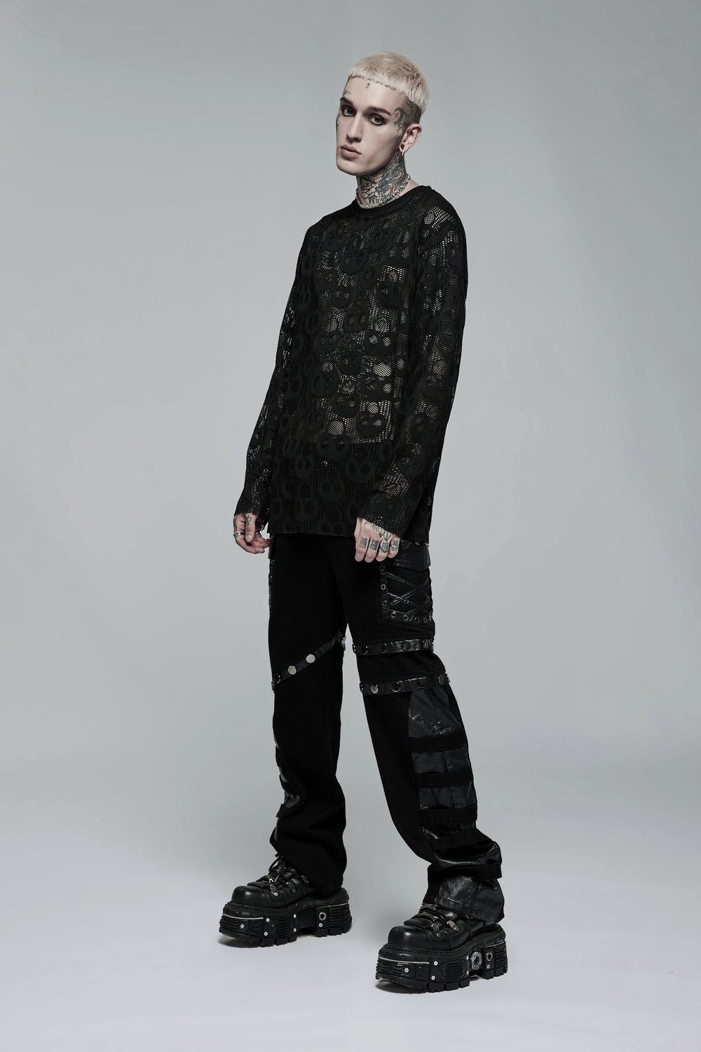 Punk style male model wearing a skull mesh long sleeve top and layered pants, showcasing edgy fashion vibes.