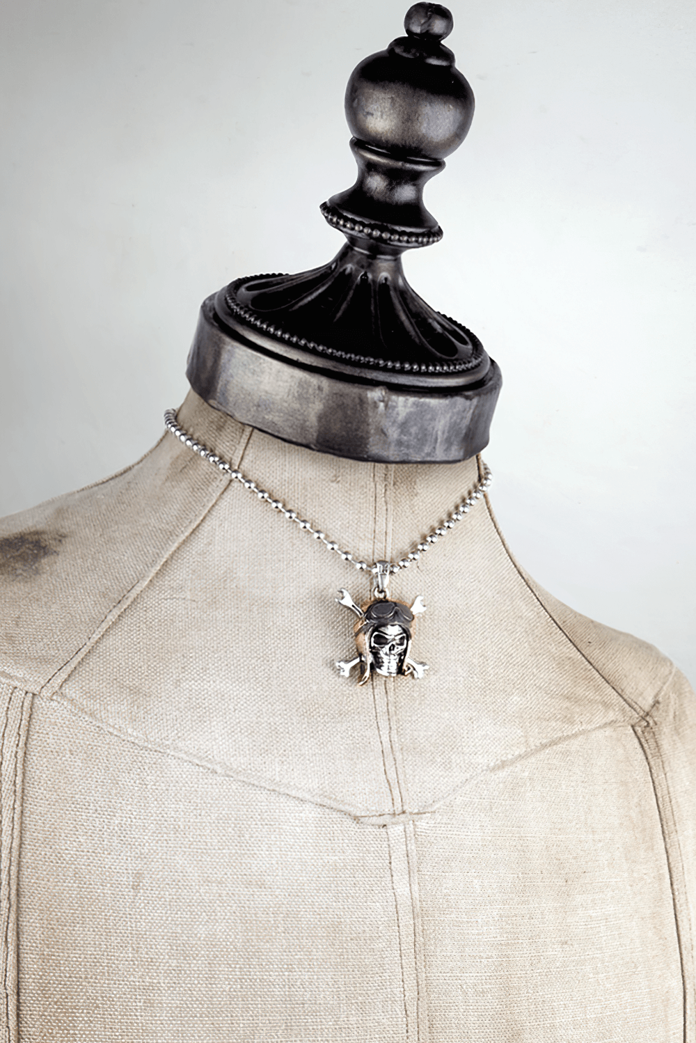 Skull Pilot Pendant with Crossed Spannerbones displayed on a vintage mannequin with a silver ball chain.