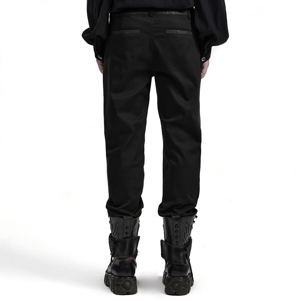 Back view of sleek black gothic slim-fit trousers with edgy webbing detail and stylish boots.