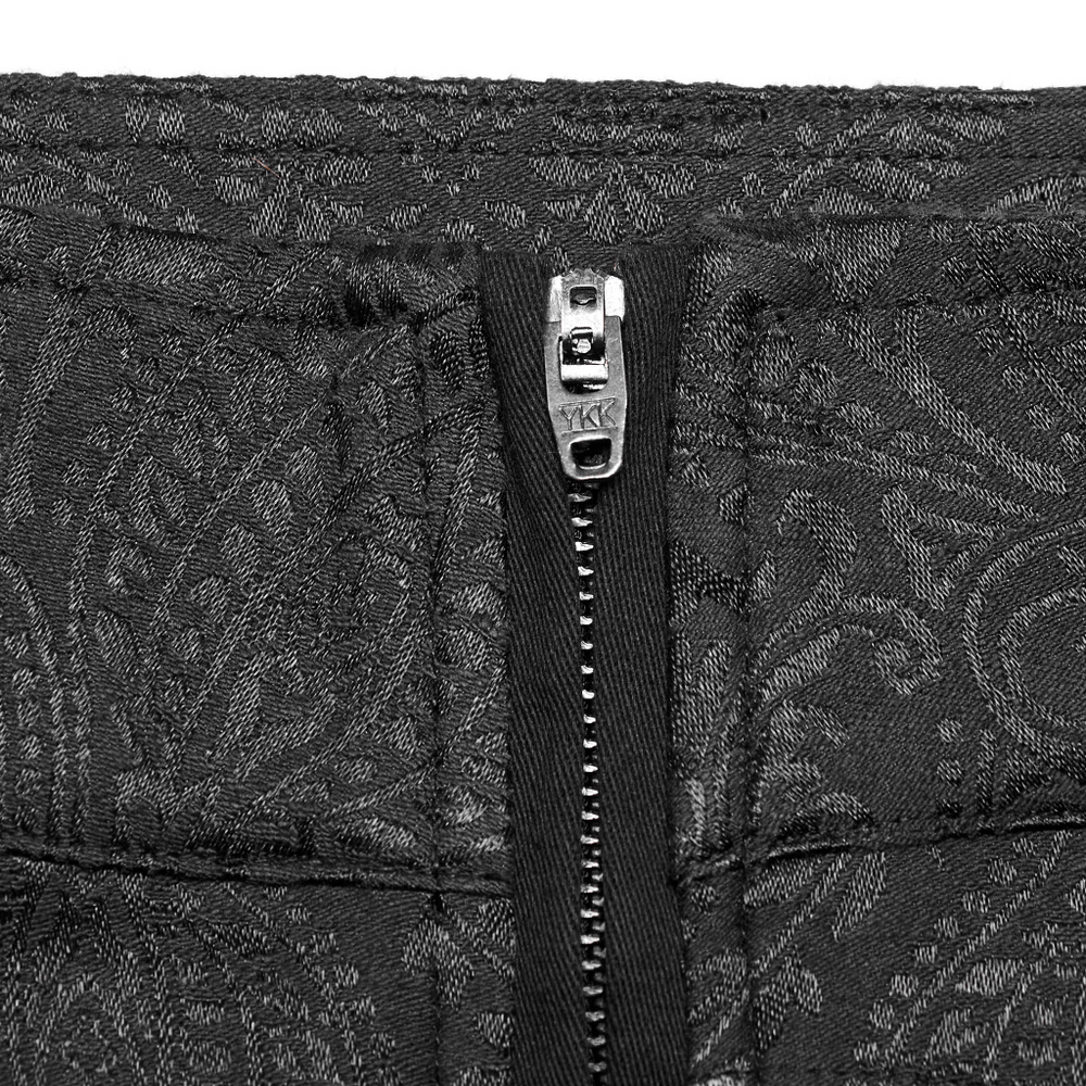 Close-up of sleek black gothic slim-fit trousers with zip detail and intricate jacquard fabric pattern.