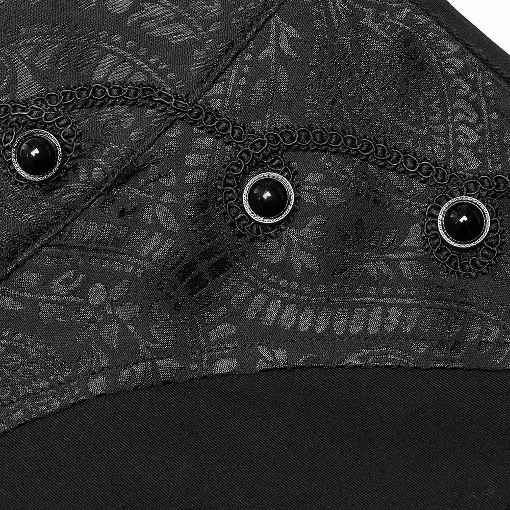 Close-up of black gothic trousers showcasing intricate fabric pattern and decorative button embellishments.