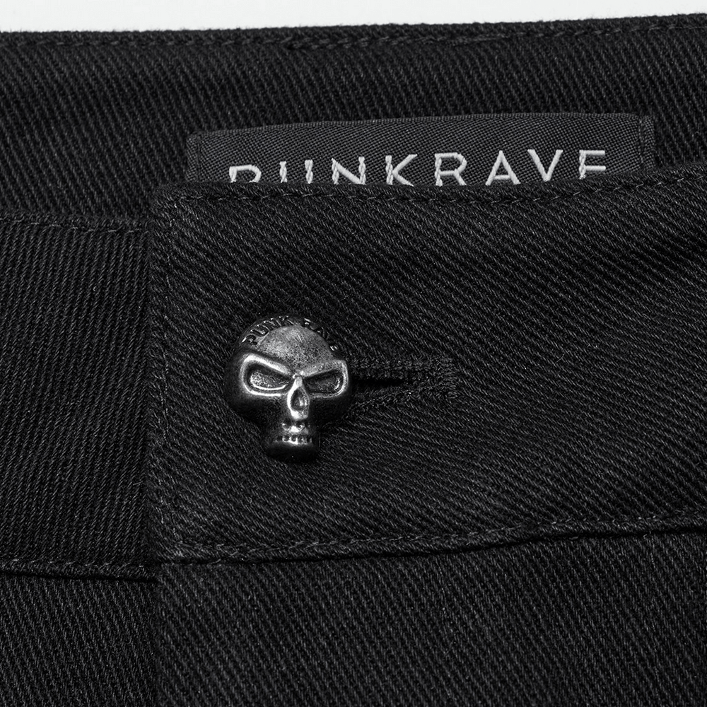 Close-up of punk-style black pants featuring a skull button and branded label for a bold Gothic look.