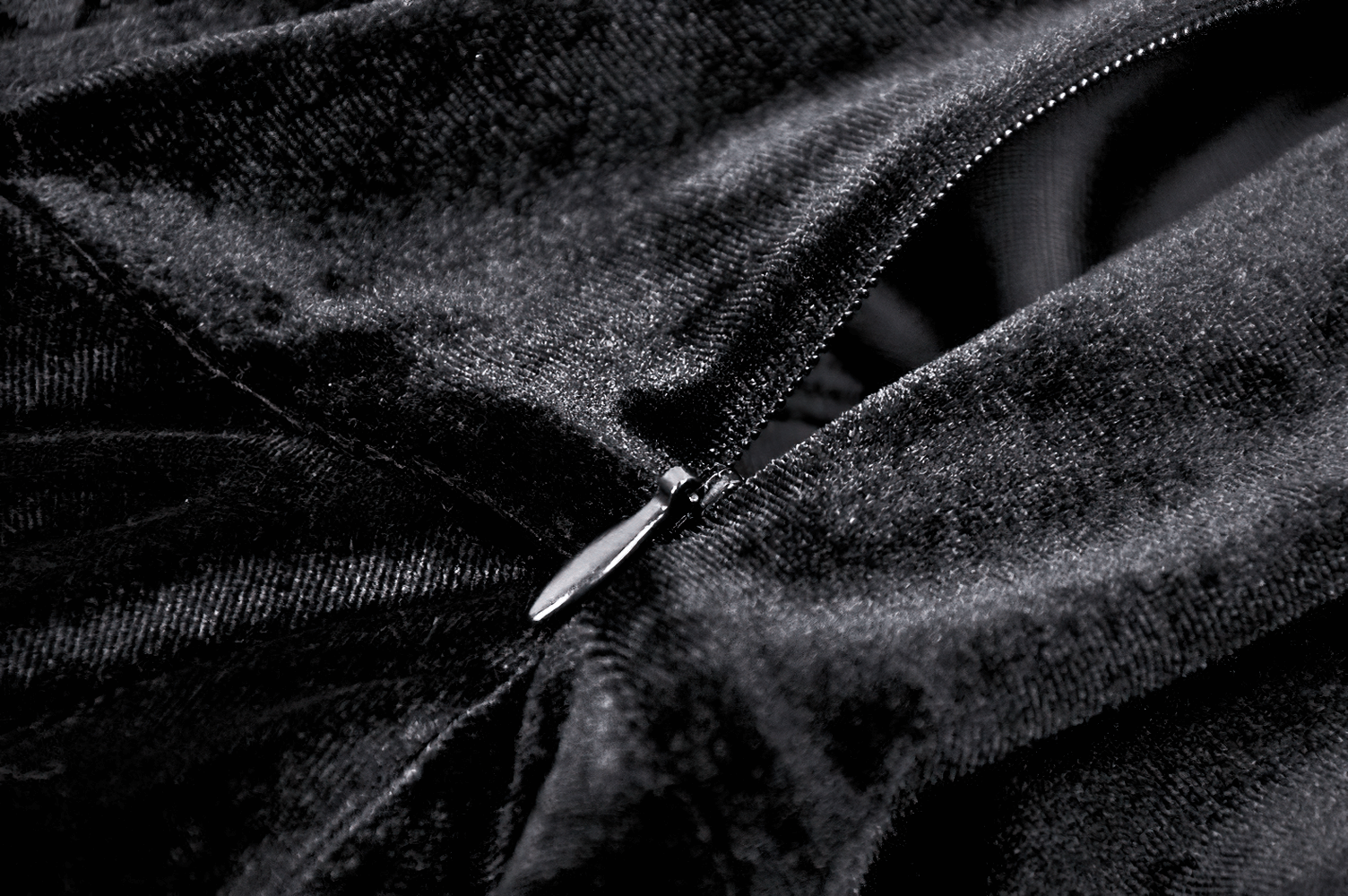 Close-up of elegant black velvet fabric with zipper detail, showcasing luxurious texture and gothic style.