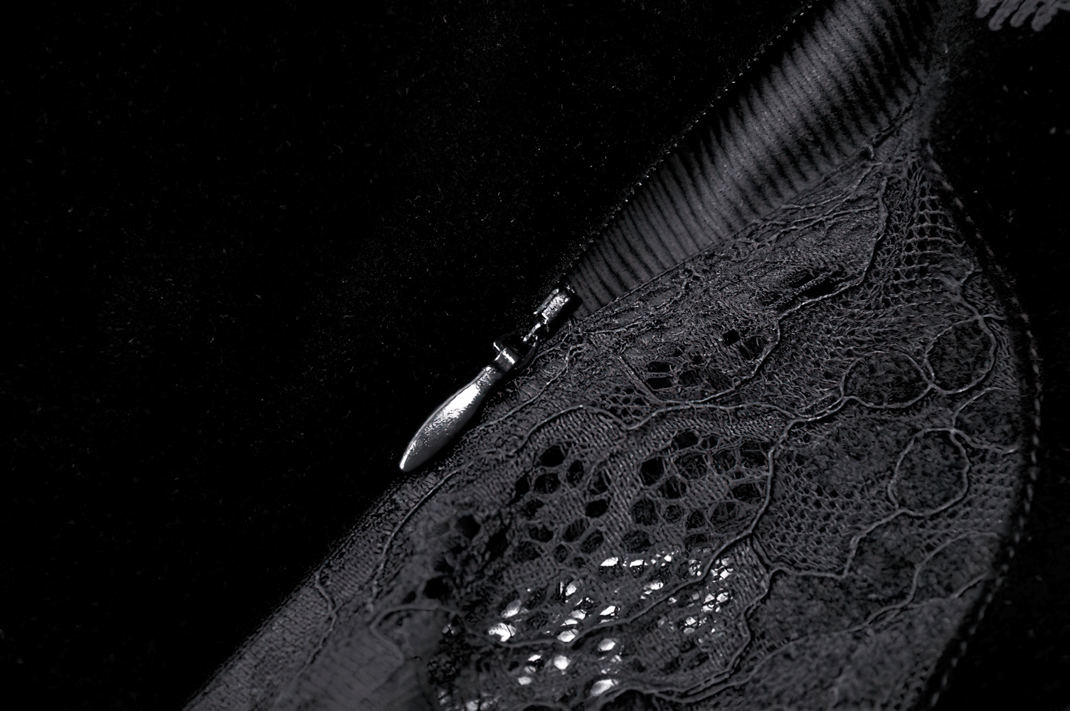 Close-up of intricate black lace and zipper detail on a dark velvet corset dress, showcasing gothic elegance.