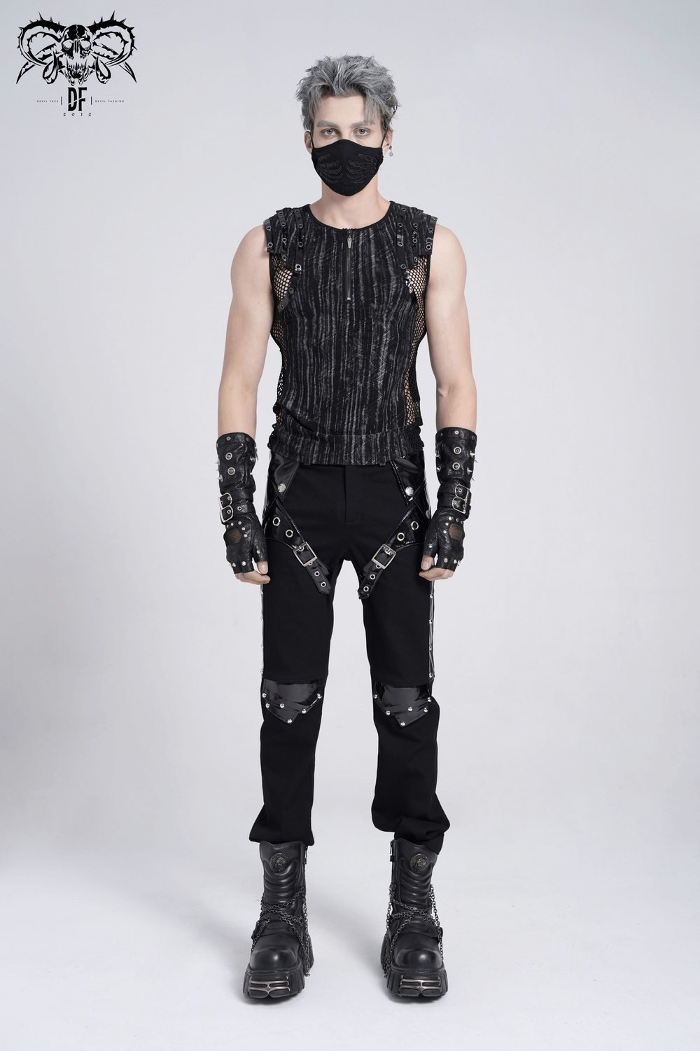 Punk grunge model wearing a sleeveless gothic top with mesh sides, buckle straps, and combat boots.