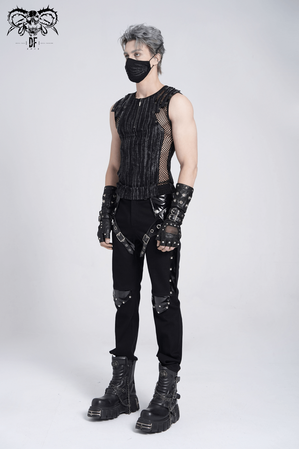 Model showcasing a sleeveless gothic top with mesh sides, buckle straps, and grunge-inspired pants in black.