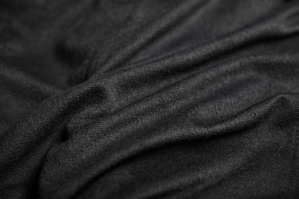 Close-up of luxurious black fabric showcasing a soft, smooth texture, perfect for Gothic styles and elegant cloaks.