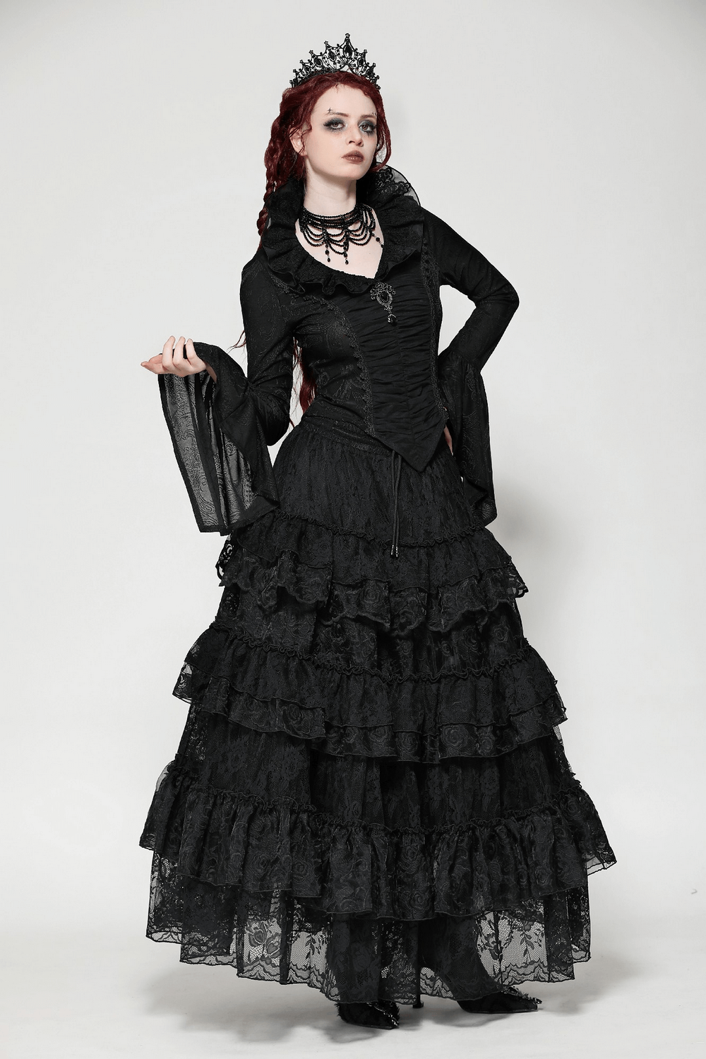 Stylish model in a black lace tiered skirt with ruffles, elegant top, and crown, perfect for gothic and formal occasions.