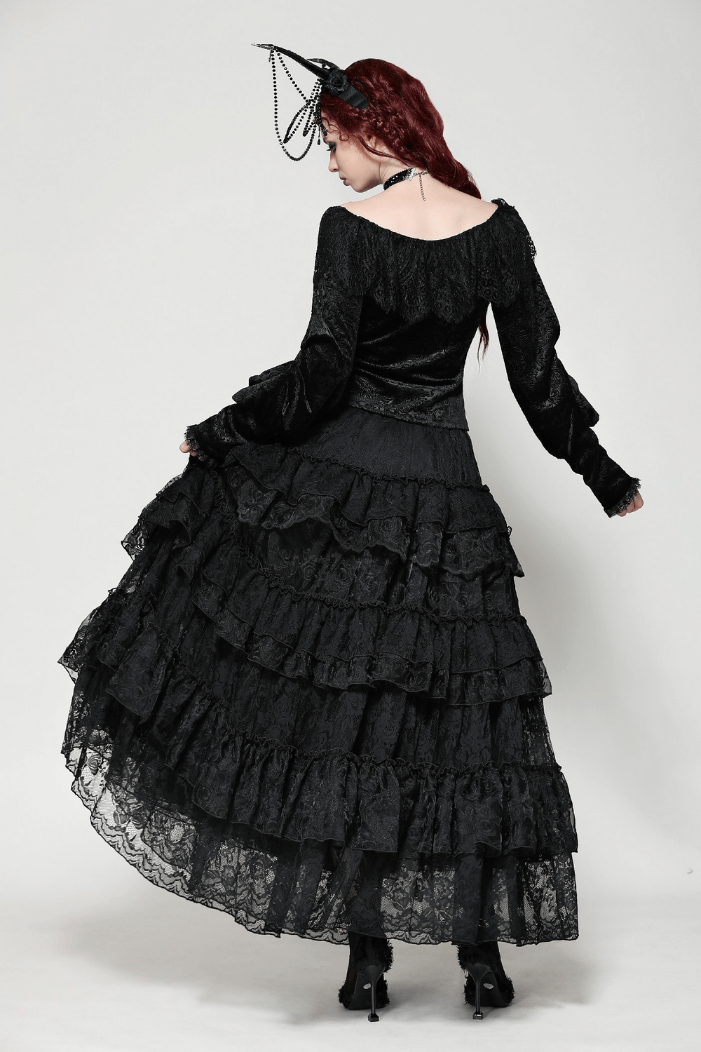 Elegant woman in a black lace tiered skirt with ruffle details, showcasing a gothic-inspired outfit with dramatic style.