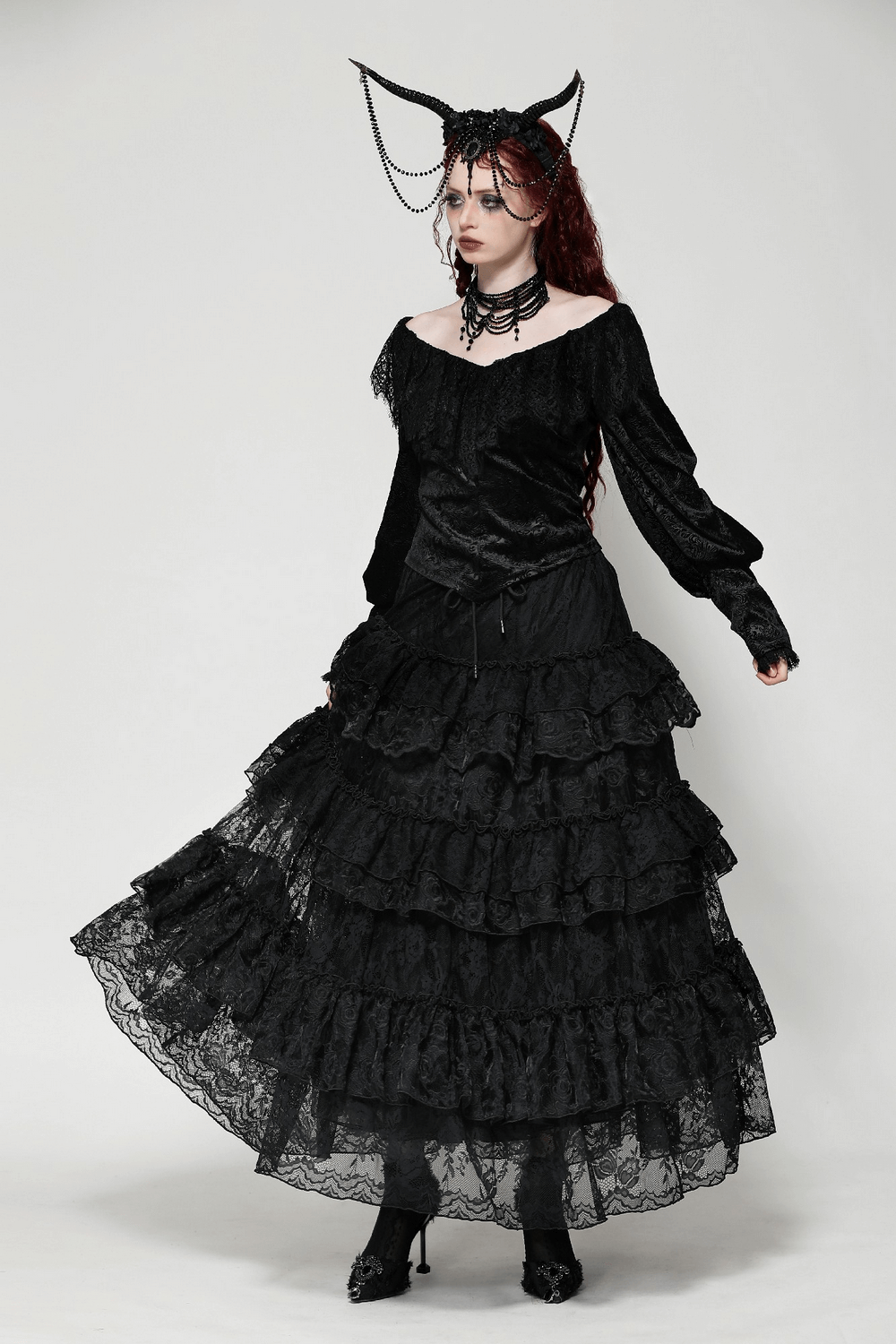 Elegant model in a black lace tiered skirt with ruffles, showcasing sophistication and style against a neutral backdrop.