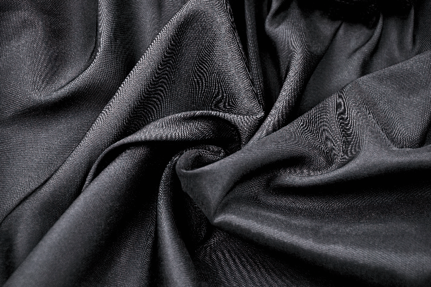 Close-up of luxurious black fabric with smooth texture, perfect for elegant garments like skirts and dresses.