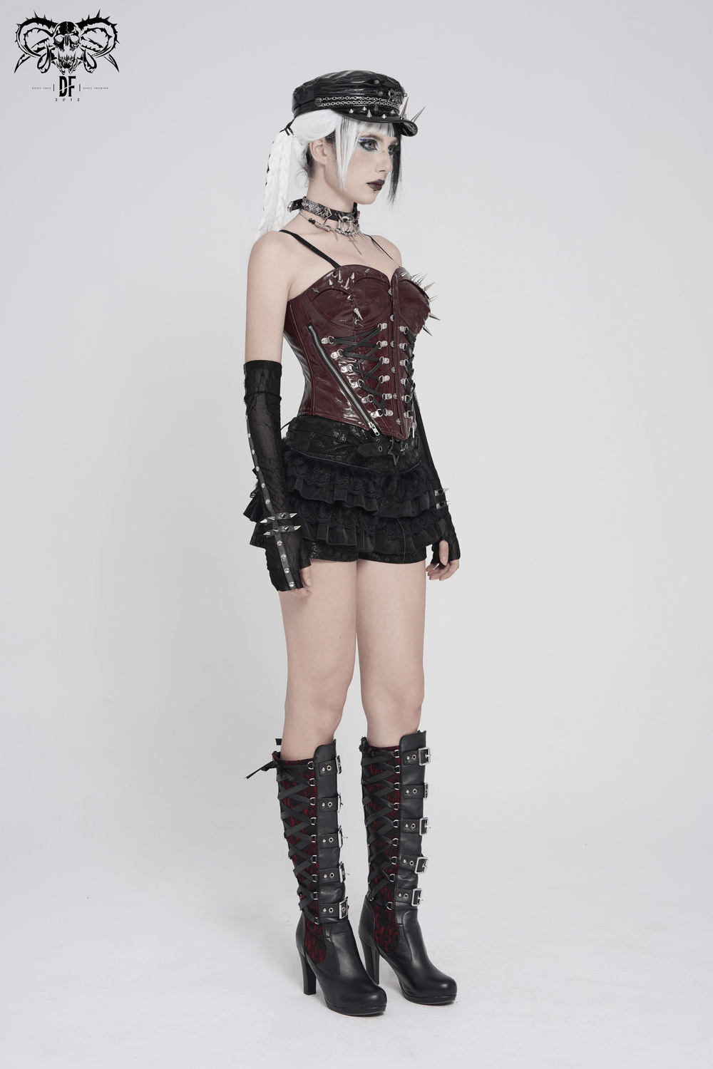 Spiked Burgundy Faux Leather Gothic Corset Top with Zips worn with a stylish black skirt and knee-high boots, embodying punk aesthetics.