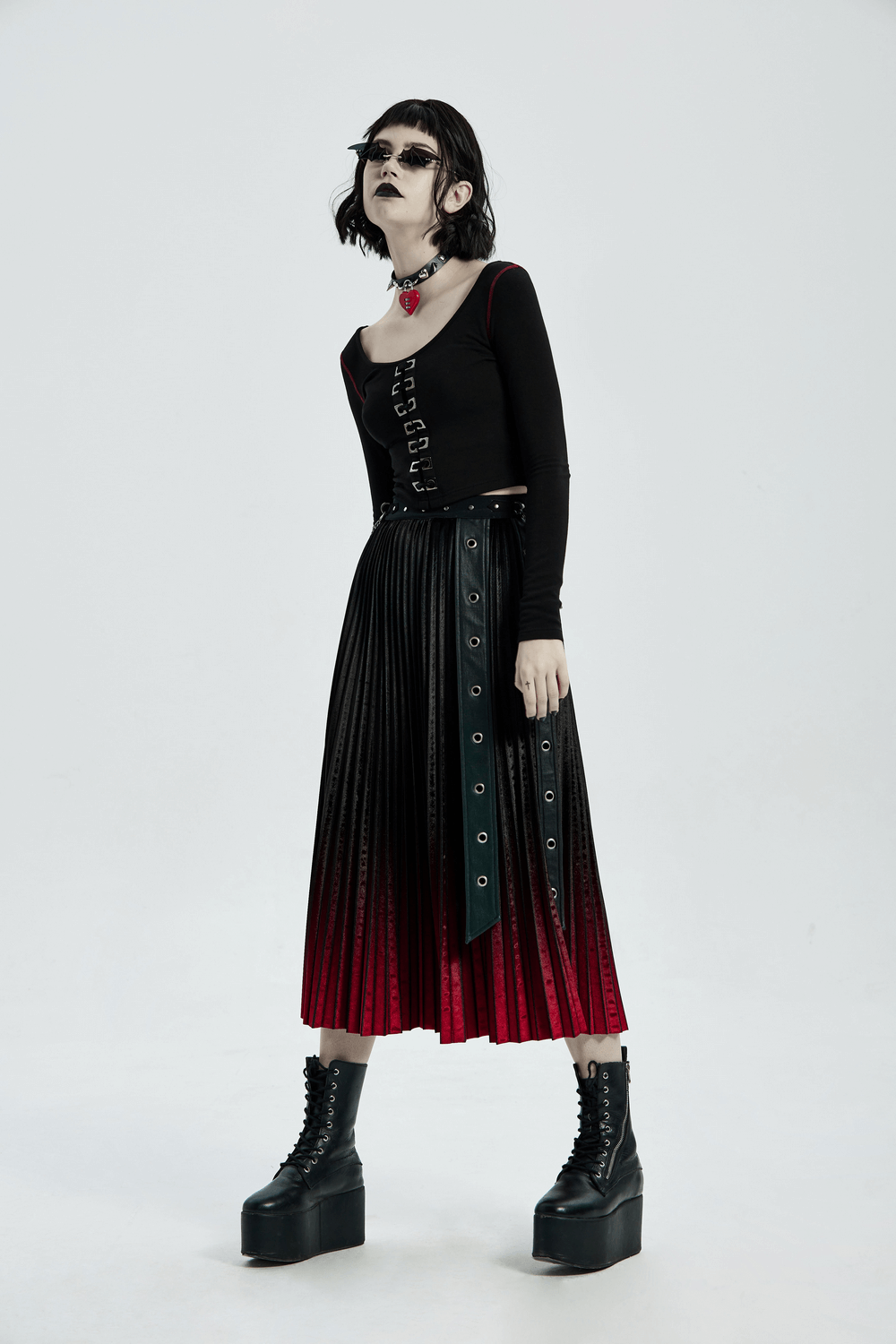Edgy punk outfit featuring square eyelet crop top and pleated skirt with black and red gradient, paired with platform boots.