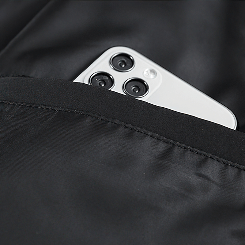 Close-up of a smartphone nestled in the pocket of a sleek black bomber jacket.