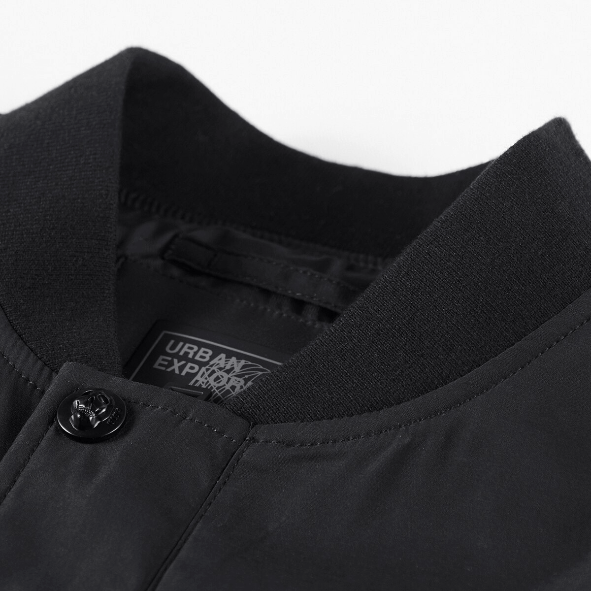 Close-up of a stand collar on a stylish black bomber jacket with a button, showcasing modern design.