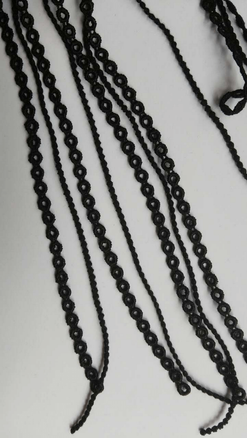 Close-up of black decorative trim with loops, perfect for fashion accessories or DIY projects.