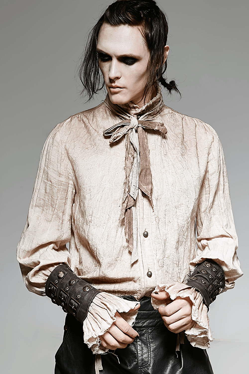 Model in a wrinkled blouse showcasing steampunk brown rivet buckle armor bracers for gothic fashion.