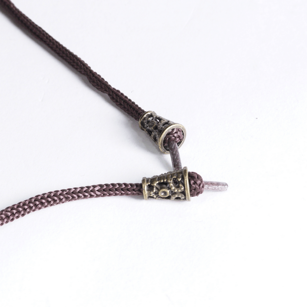 Close-up of a braided brown cord with decorative metal clasp ends, perfect for jewelry or accessory designs.