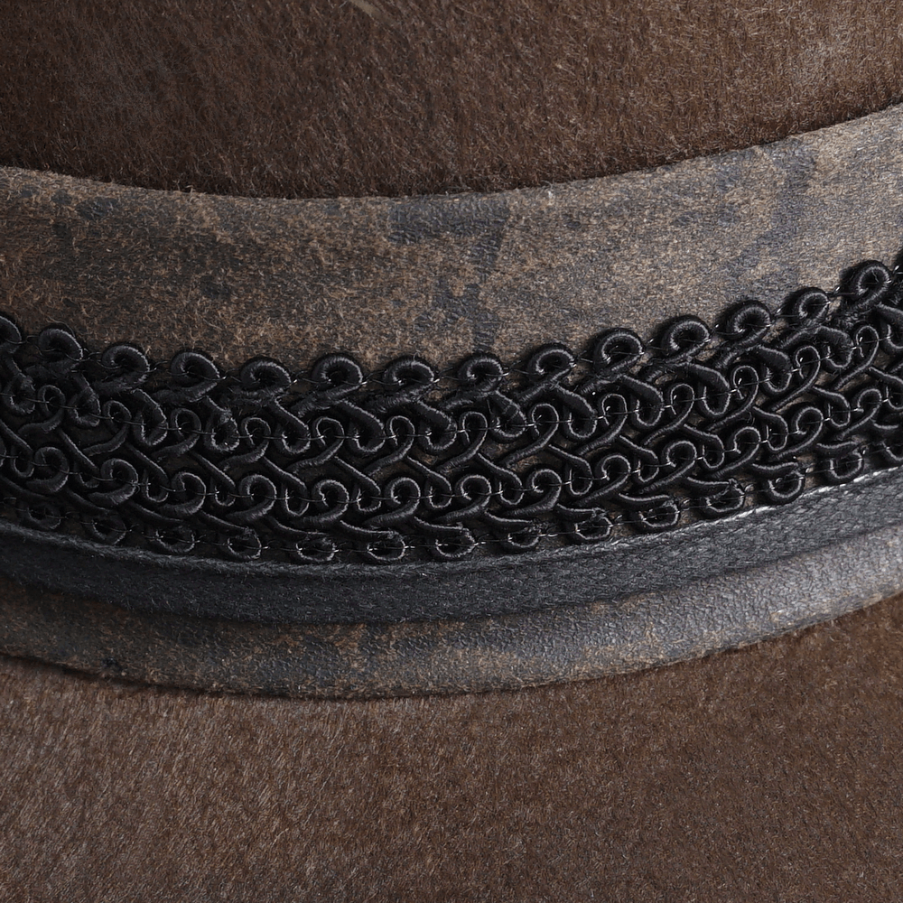 Close-up of a vintage steampunk brown hat with intricate black detailing and embellishments.