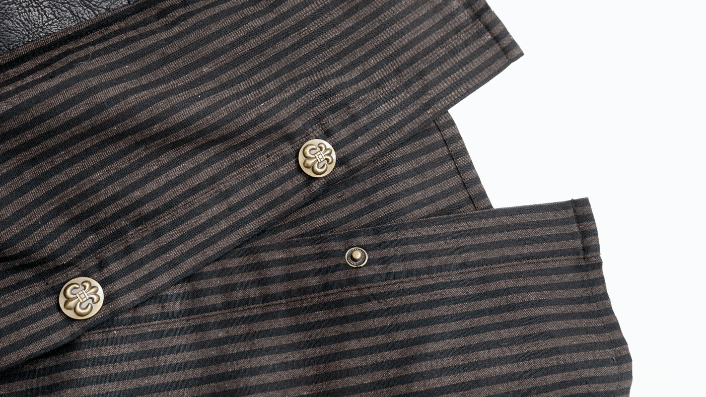 Close-up of a steampunk striped shirt featuring unique buttons and PU leather inserts, perfect for vintage fashion lovers.