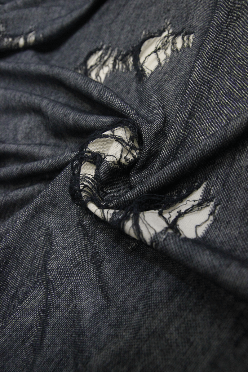 Close-up of frayed black fabric showing a torn design, perfect for steampunk and gothic-inspired fashion.