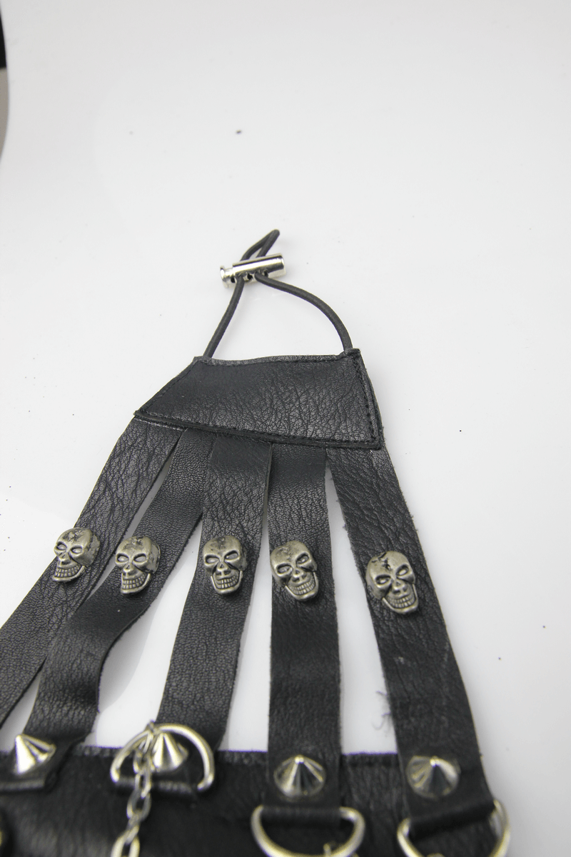 Close-up of a steampunk men's mask detail featuring black straps with silver skulls and spikes.