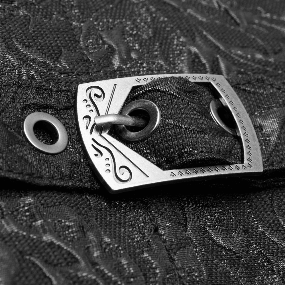 Close-up of steampunk waistcoat's ornate buckle on black embroidered fabric.