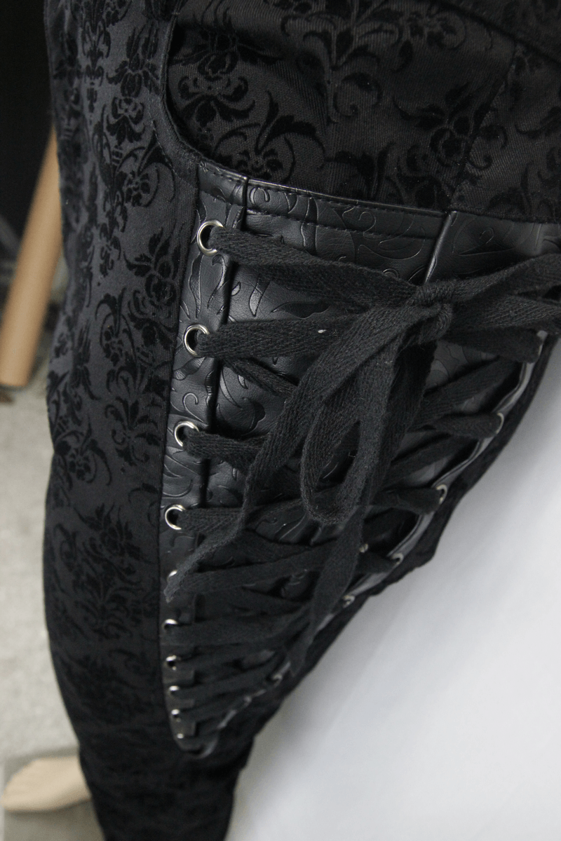 Close-up of gothic black slim pants featuring lace-up sides and elegant vintage pattern.