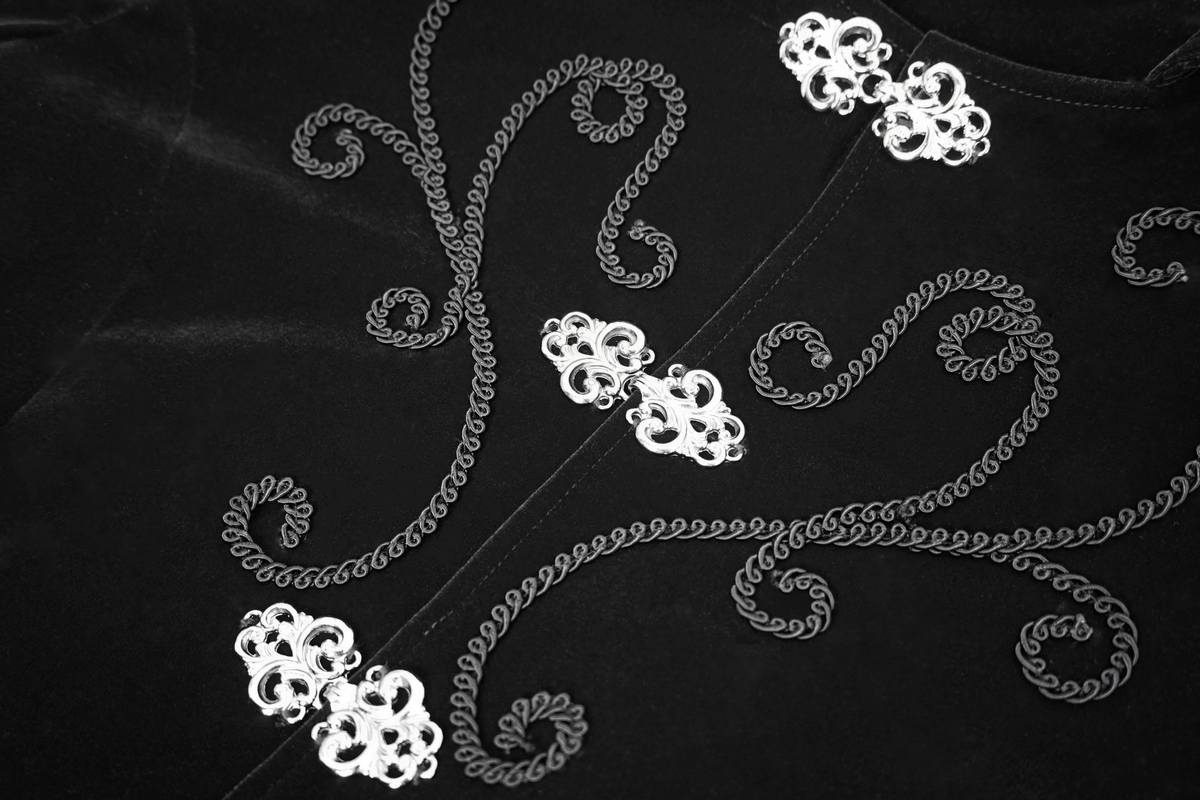 Close-up of silver button embellishments on a black velvet steampunk coat, showcasing intricate design.
