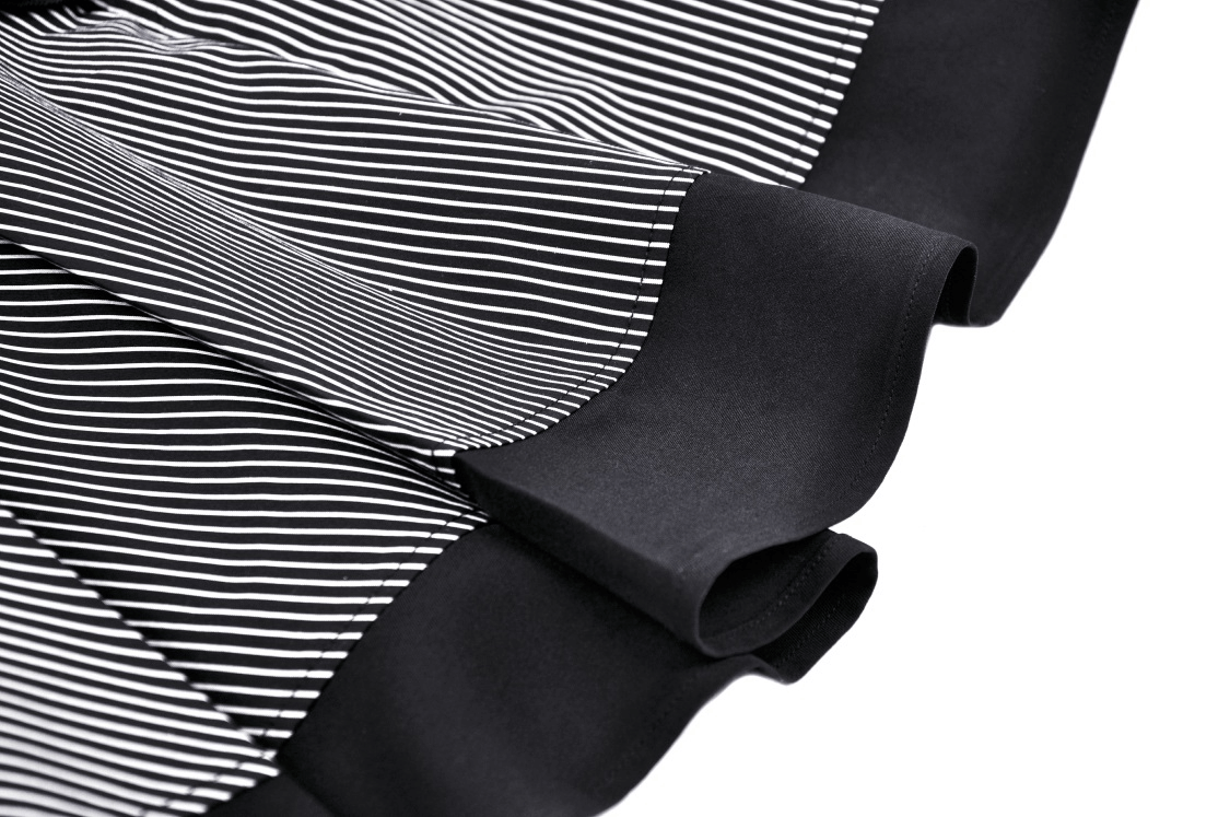 Close-up of the ruffled sleeve and pinstripe detail of a chic steampunk dress featuring a pleated skirt.