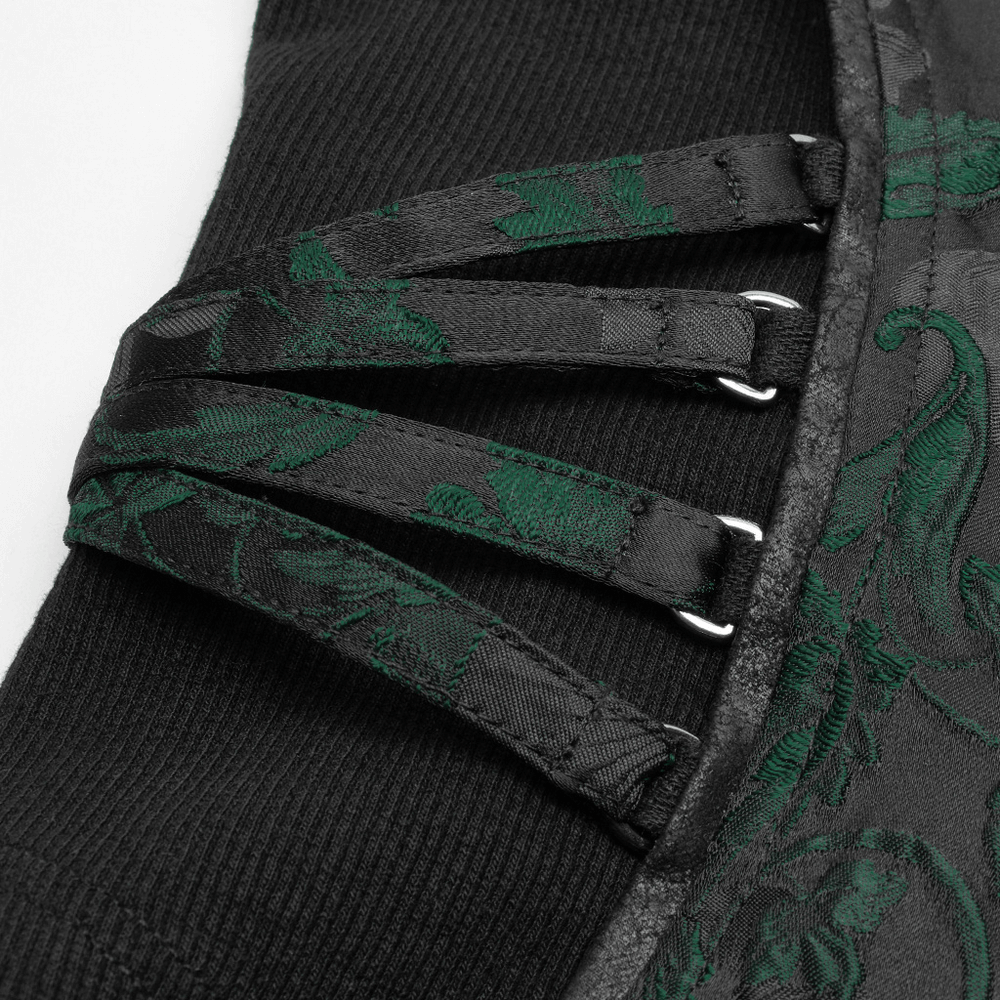 Close-up of steampunk waistcoat buckles and lace detailing on black jacquard fabric with green vine pattern.
