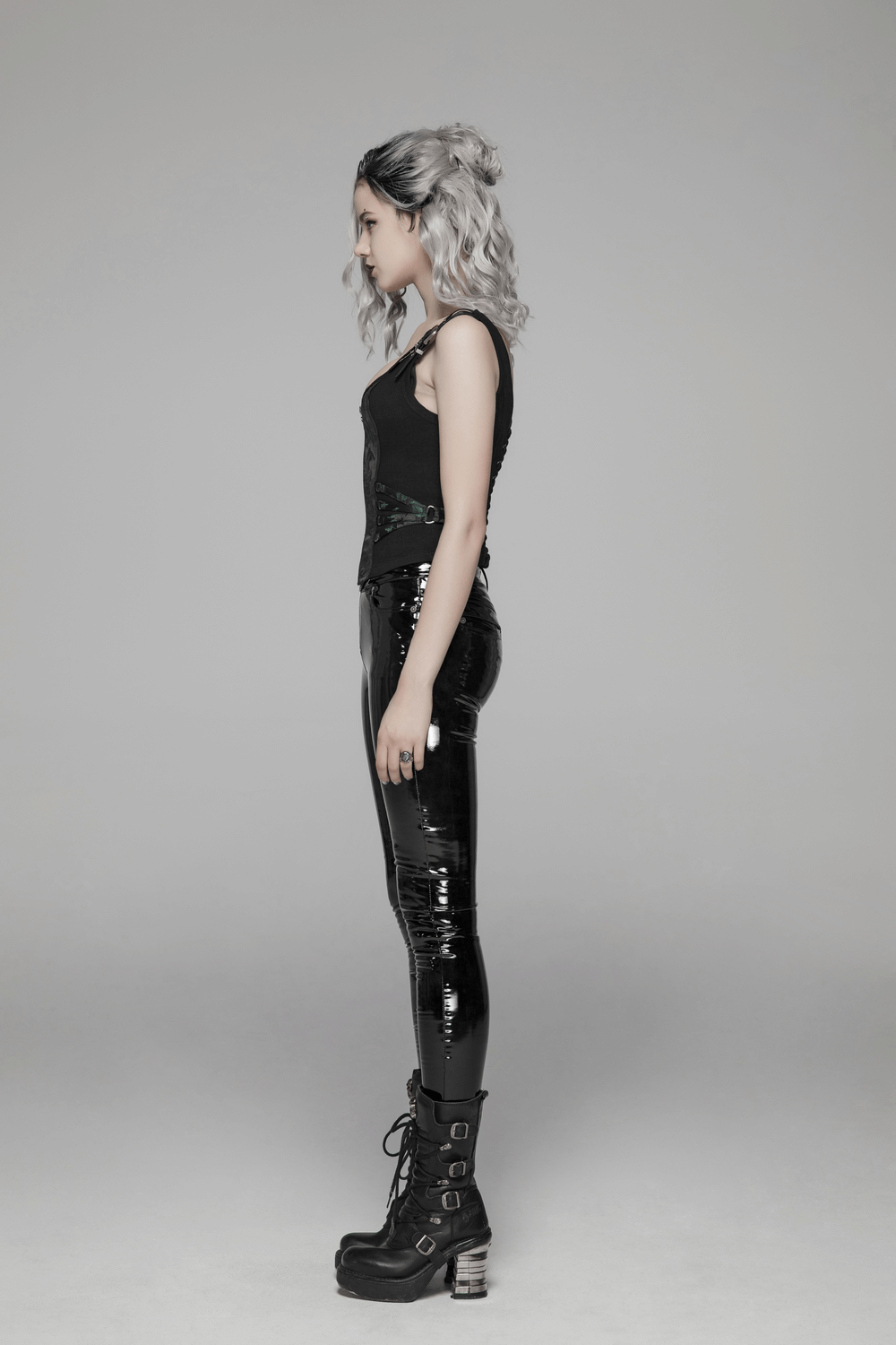 Side view of a stylish model in a black fitted top and glossy black pants, showcasing a modern edgy look.