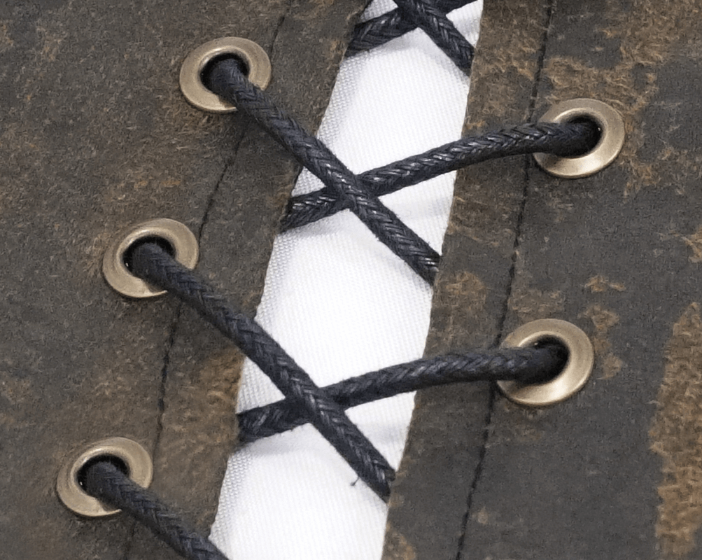 Detail of steampunk vest showing bronze rivets and lace-up design on brown PU leather.